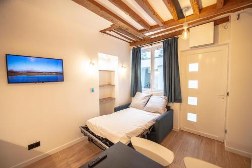 巴黎Appartement cosy Montorgueil (Bonne Nouvelle)的小房间设有一张床和墙上的电视