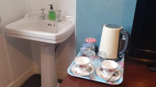 布罗克斯本Kingsway Bed & Breakfast的一间带水槽的浴室和一个带杯子的托盘