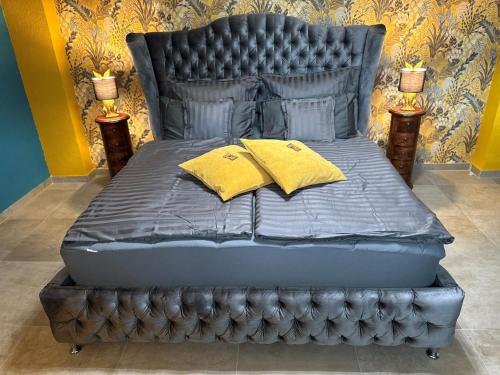 GroßweitzschenPalais -MehrGehtNicht-Maisonette的一张黑色的床,上面有两个黄色枕头