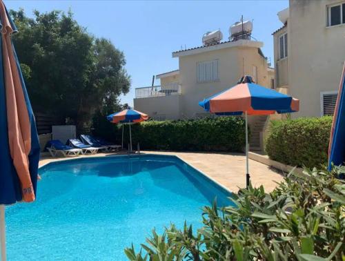 帕福斯Kato Paphos 2 Bedroom House - Tourist location的一座游泳池,旁边设有两把遮阳伞