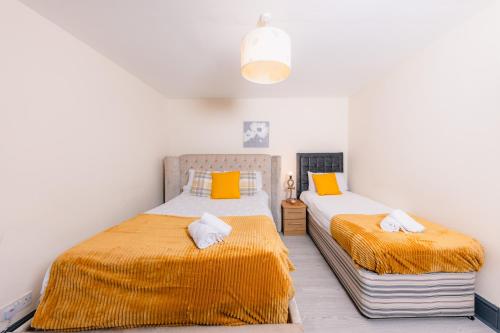 爱丁堡Warm&Welcoming City Centre Apartments by Meadows 7的一间卧室配有两张带橙色和白色床单的床