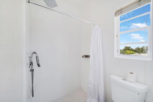 迈阿密Treehouse Hotel的带淋浴的白色浴室和窗户。