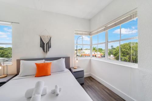 迈阿密Treehouse Hotel的白色卧室配有带橙色枕头的大床