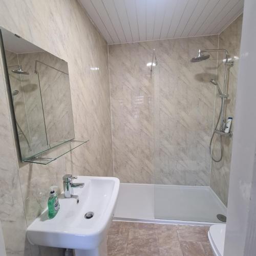 CowdenbeathThe Beath Inn的浴室配有水槽、淋浴和浴缸。