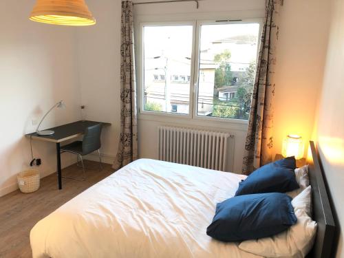 图卢兹Maison confortable et calme/5 chambres & 6 SdB的一间卧室配有一张带蓝色枕头的床和一扇窗户。