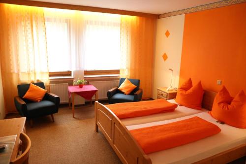 Burbach贝赫特酒店的一间卧室配有两张床和两把椅子