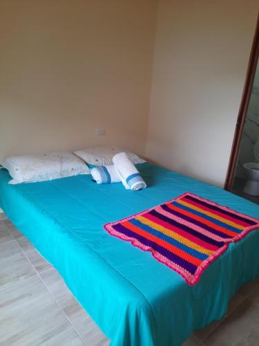 巴里查拉Habitación con baño privado的蓝色的床,上面有五颜六色的毯子
