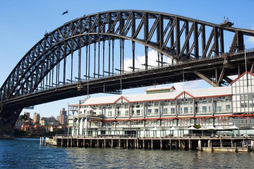 悉尼悉尼港1号码头傲途格精选酒店的水面上的桥梁,下面有一座建筑物