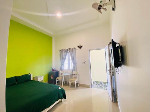 潘切Homestay BONO Mũi Né的一间带绿色墙壁的卧室、一张床和电视