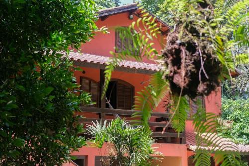 佩尼多Casa em penedo com cachoeira的前面有树木的红色建筑