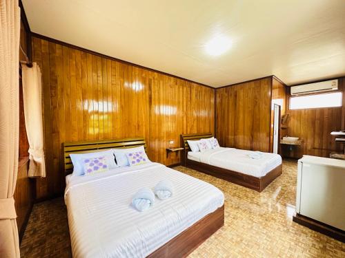 Tok PhromBann Klong Jao Homestay的木墙客房的两张床