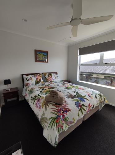 图朗伊Modern House near Motuoapa Tongariro Crossing fishing skiing的一间卧室配有一张带花卉床罩的床和窗户。