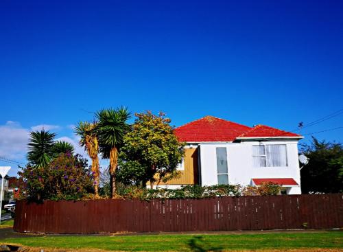 奥克兰Nice house on Wesley Auckland的白色的房子,有红色的屋顶和栅栏