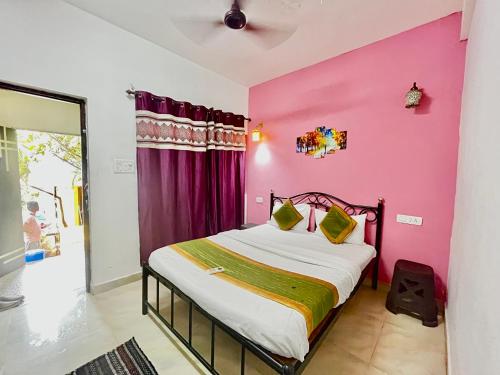 瓦加托Dipty Welcome Stay的卧室设有粉红色的墙壁和一张床