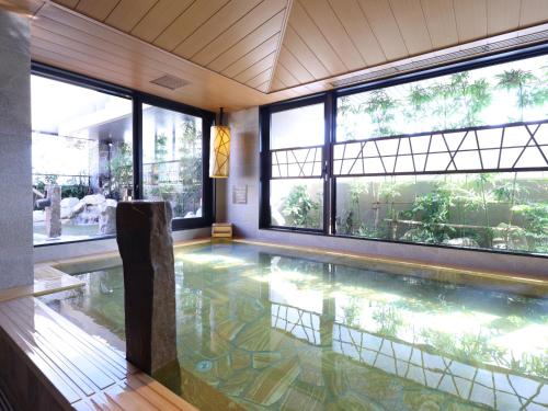 别府Beppu Hatto Onyado Nono Beppu的游泳池,位于带窗户的房间和游泳池