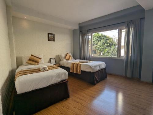 帕坦Nyadha House Bed & Breakfast的带窗户的客房内的两张床