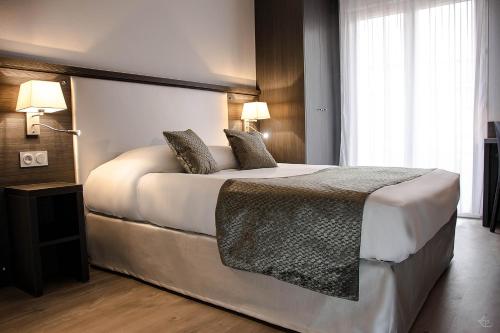 普罗旺斯艾克斯塞祖尔阿菲尔埃克斯普罗旺斯酒店的卧室配有一张带两个枕头的大白色床