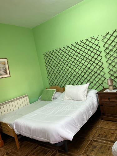 雷阿尔城Hostal Cabañeros的一间卧室设有两张床和绿色的墙壁