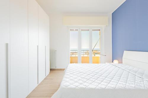 斯波托尔诺Appartamento vista mare di Marco的白色的卧室设有白色的床和窗户。