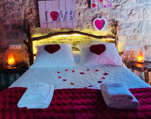 ChertCasa Rustic Suites, JACUZI & LOVE的一间卧室配有一张带心形枕头的床