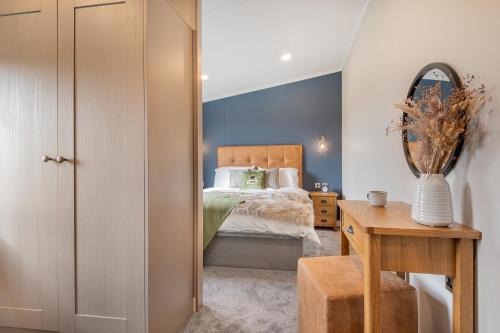 巴森斯韦特Oak Tree Timber Holiday Lodge的一间卧室配有一张床和一张带镜子的桌子