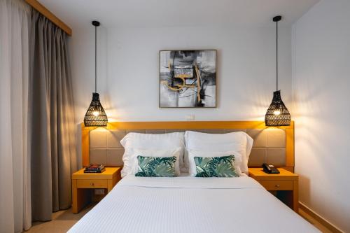 阿基欧斯尼古拉斯Ariadne Beach - Adults Only的一间卧室配有一张带2个床头柜和2盏灯的床。