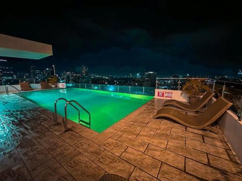 宿务Chillhauz Staycation Cebu的一座游泳池,在晚上在一座建筑的顶部