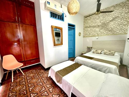 圣玛尔塔Hotel Kasaya Real的一间设有两张床和椅子的房间