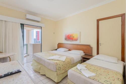 累西腓Flat Costa Mar的酒店客房设有两张床和窗户。