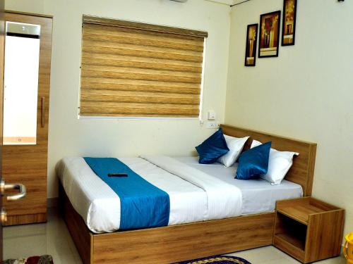 科泽科德MARHABA PALACE的一间卧室配有一张带蓝色枕头的床和一扇窗户。
