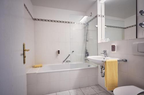 肯普滕MY公园酒店的白色的浴室设有浴缸和水槽。