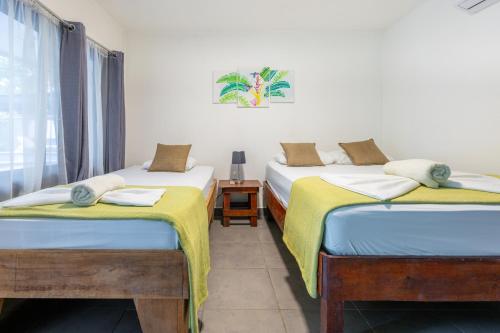 托尔图格罗La Casona Eco-Lodge Tortuguero的带窗户的客房内设有两张单人床。