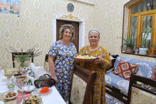 希瓦Khiva Ibrohim Guest House的两名妇女站在一间有一盘食物的房间