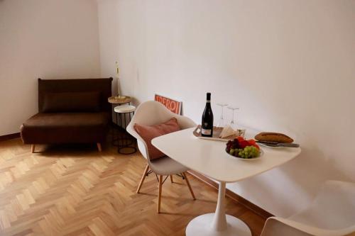 阿奎泰尔梅Cozy Flat in Piemonte的一张带一碗水果和一瓶葡萄酒的白色桌子