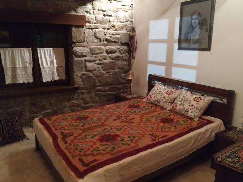VláchaΠαραδοσιακή πέτρινη κατοικία στην Βλάχα Ελάτης的一间卧室配有一张红色棉被的床