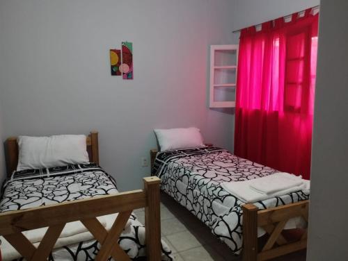 门多萨HOSTAL HOUSE REYMON,habitaciones privadas" precio por persona"的带红色窗户的客房内的两张床