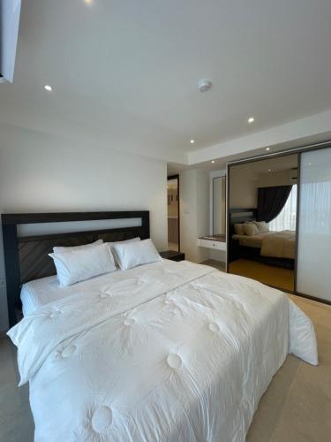 阿克拉Solaris Appartment 5&7th floor的卧室内的一张大白色床,配有镜子