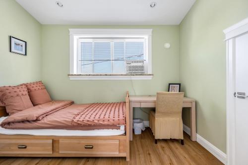 温哥华Three bedrooms brand new laneway house near public transit的一间卧室配有一张床、一张书桌和一个窗户。