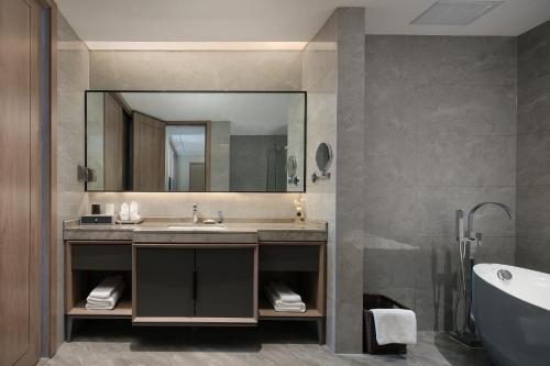 张家界张家界专家村阳光庭院酒店的浴室配有盥洗盆、镜子和浴缸