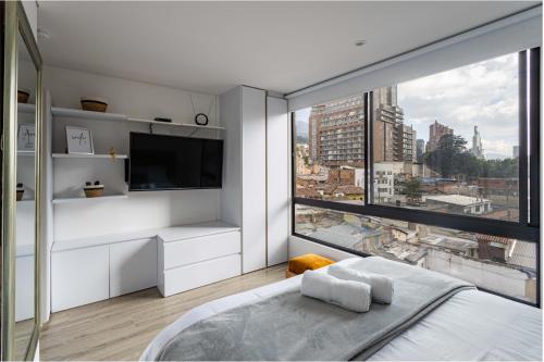 波哥大Loft nuevo, moderno, central的白色卧室设有大窗户和电视