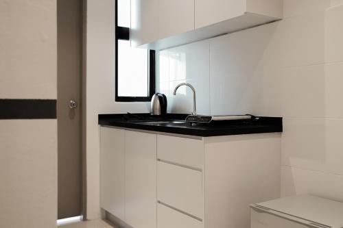 东贡岸ITCC Manhattan Suites by Pinstay Premium的白色的厨房设有水槽和窗户