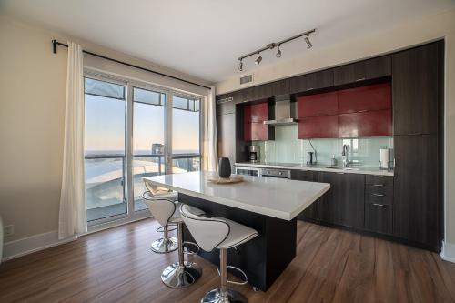 多伦多Designer condo w/ CN Tower view & parking的一个带大岛和两个凳子的厨房
