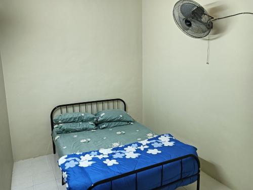 斯里伊斯兰德Homestay Itqan Seri Iskandar的一张带蓝色棉被和风扇的床