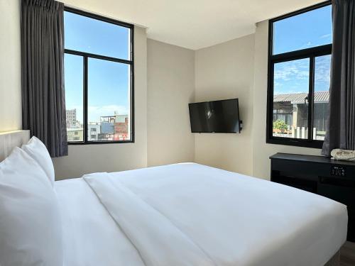 Dajia福棧 Full.Inn的卧室设有一张白色大床和两个窗户。