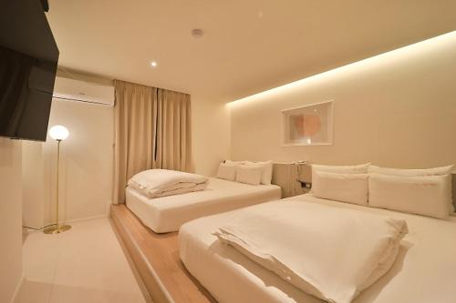 釜山Hotel Yam Yeonsan的一间卧室配有两张床和一台平面电视
