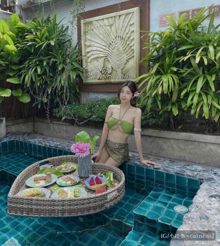 马六甲The Kembali Luxury Villa - Melaka 5 Bedroom的坐在游泳池前的比基尼女人