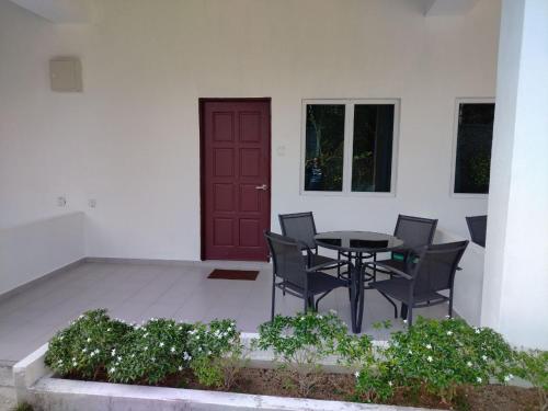 珍南海滩FUNDUQ AL BUSYRA的一个带桌椅的庭院和一扇红色的门