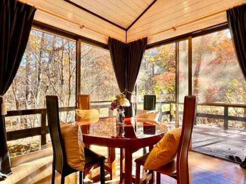 北轻井泽虹の街22北軽井沢#Luxurious Kita Karuizawa private villa的一间带桌椅和大窗户的用餐室