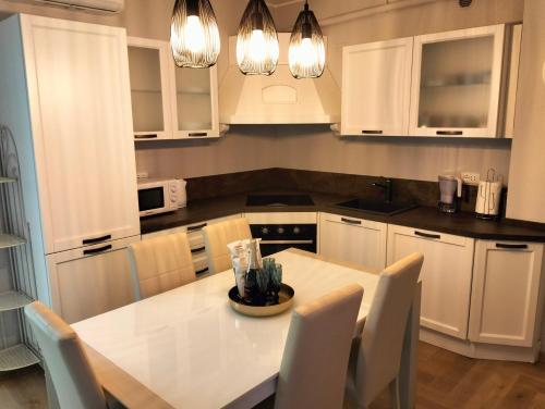 佩萨罗Appartamento LA RIBOLLITA的厨房配有白色橱柜和白色的桌椅