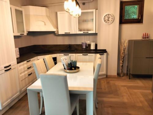 佩萨罗Appartamento LA RIBOLLITA的厨房配有白色橱柜和桌椅